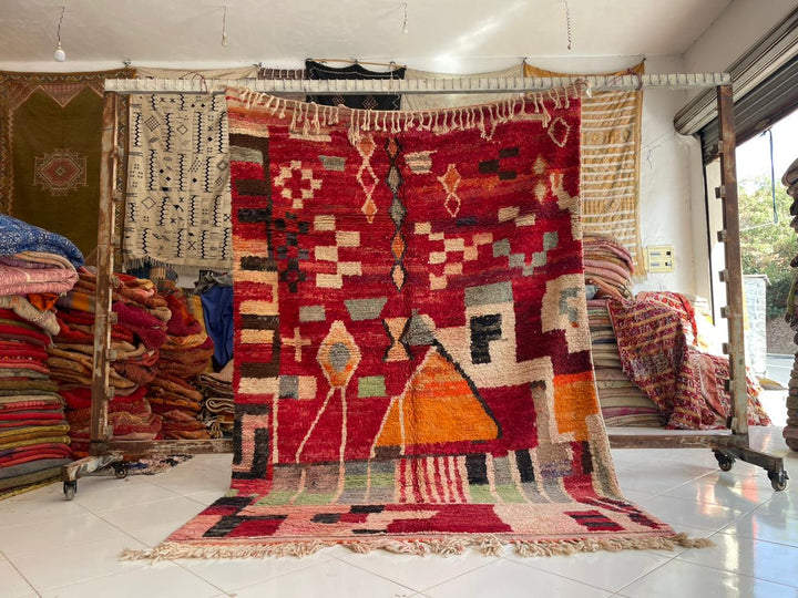 Lifestyle shot of a vintage Moroccan rug featuring geometric patterns in red and orange.