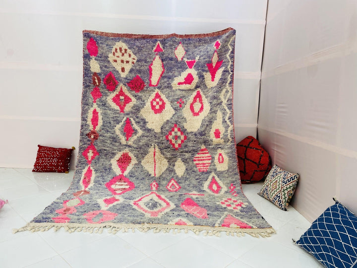 Lifestyle shot of a red vintage Boujaad Moroccan rug with tribal patterns on a white background.
