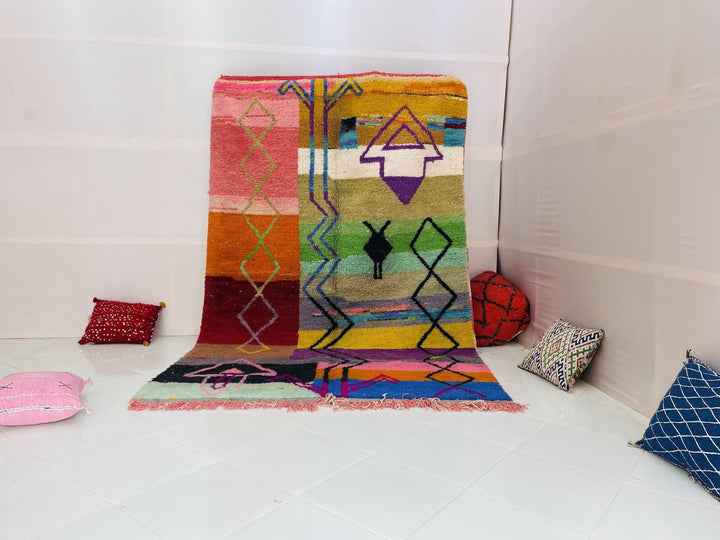 Lifestyle shot of a purple and pink abstract Moroccan rug on a white background.
