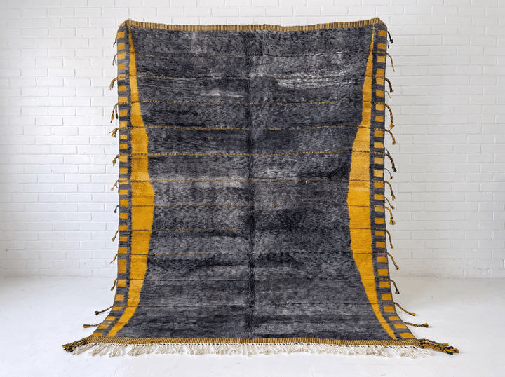 Front view of the dark grey Moroccan rug with fringe edges on a white background.