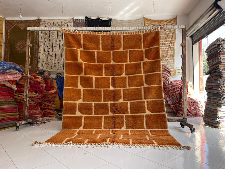 Lifestyle shot of a vintage Moroccan rug with geometric patterns in brown and white.