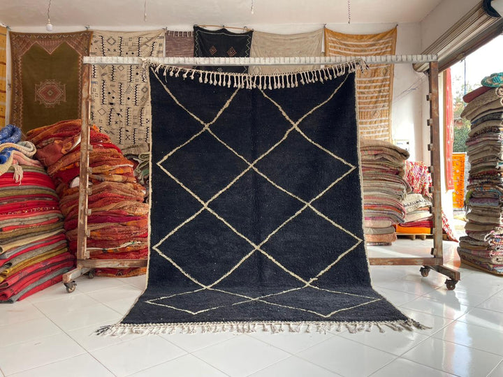 Lifestyle shot of the black Beni Ourain rug featuring geometric patterns and fringe edges.