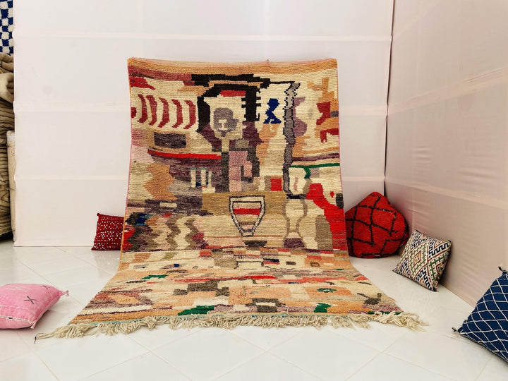 Lifestyle shot of the Moroccan Boujaad rug featuring tribal patterns in beige, red, and blue.