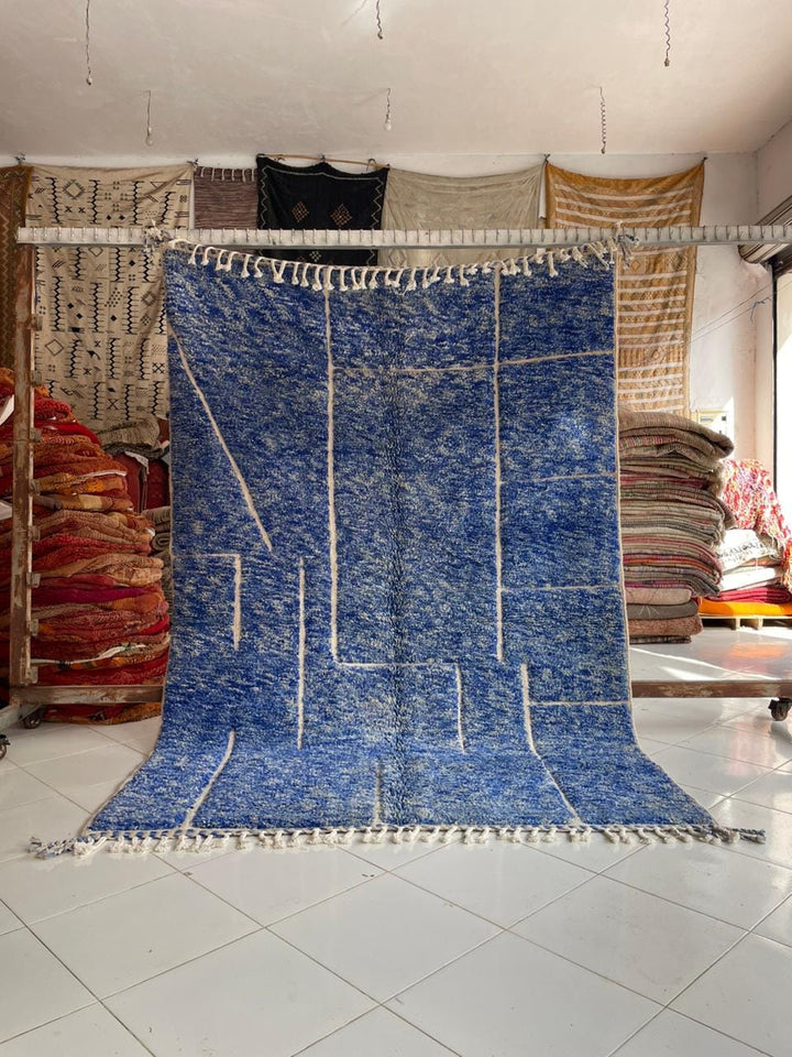 Lifestyle shot of a blue Moroccan rug with geometric patterns in a natural setting.