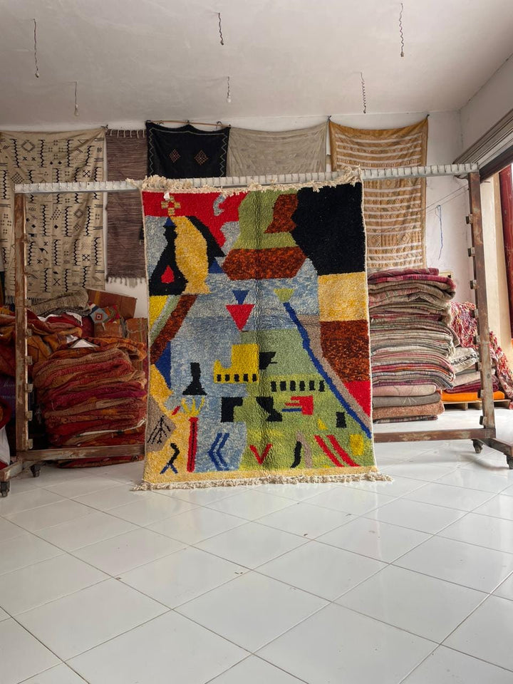 Lifestyle shot of a colorful Moroccan rug featuring geometric patterns and fringe edges.