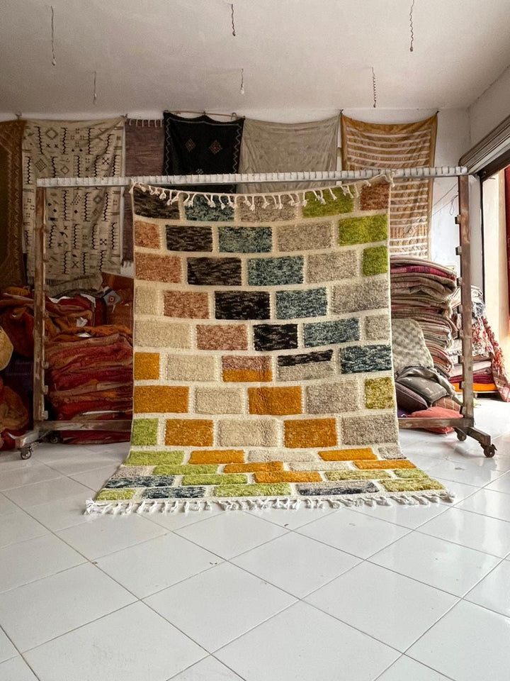 Lifestyle shot of a colorful Moroccan rug featuring orange, green, and blue hues in a natural setting.