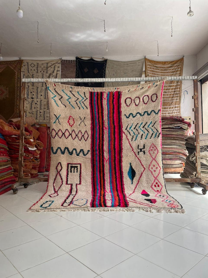Lifestyle shot of a colorful pink Moroccan rug with geometric patterns and fringe edges.