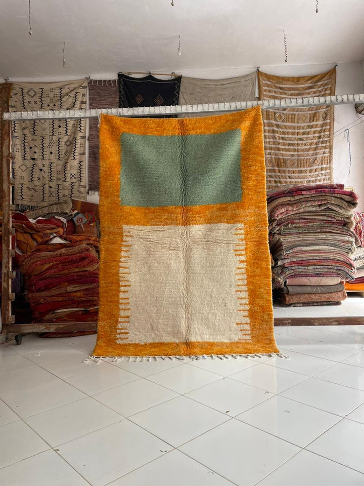 Lifestyle shot of a colorful Moroccan rug with geometric patterns in orange and green.