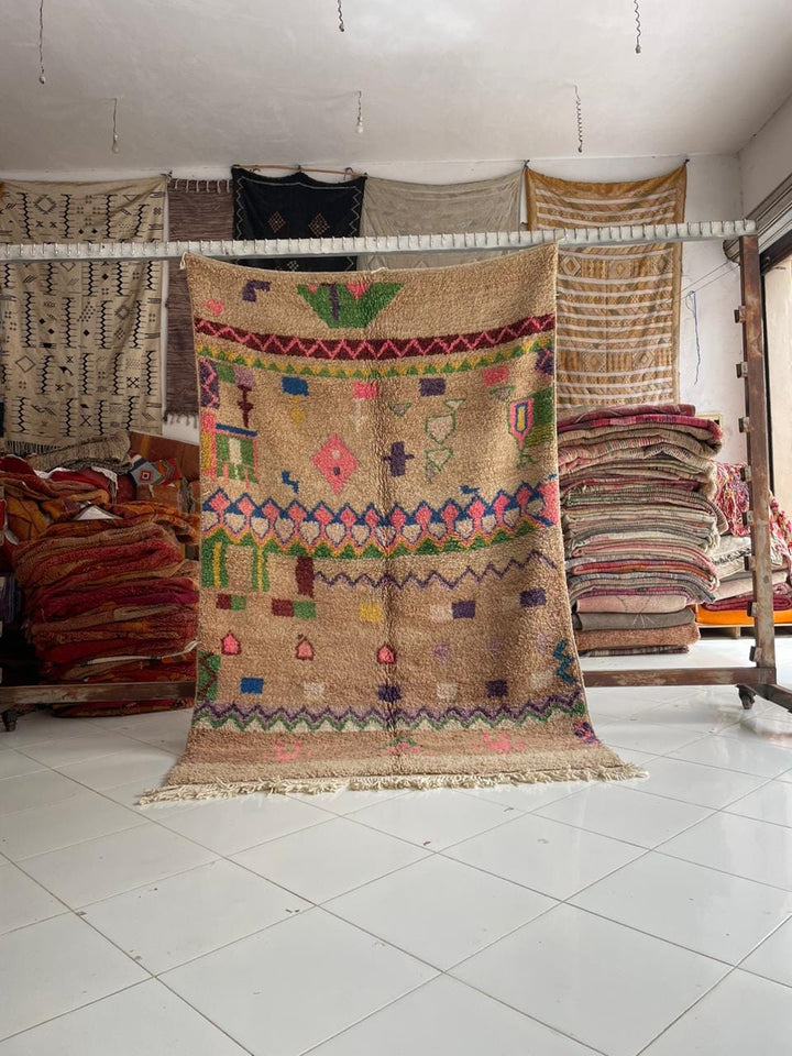 Lifestyle shot of a colorful Moroccan rug with beige, pink, green, and blue colors.
