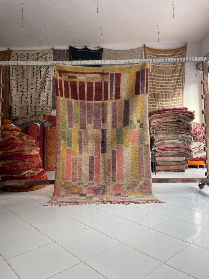 Lifestyle shot of a colorful Moroccan rug featuring red, yellow, purple, and green in a natural setting.