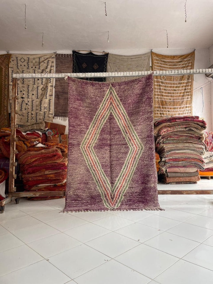 Lifestyle shot of a pink Moroccan rug featuring a diamond pattern and fringed edges.