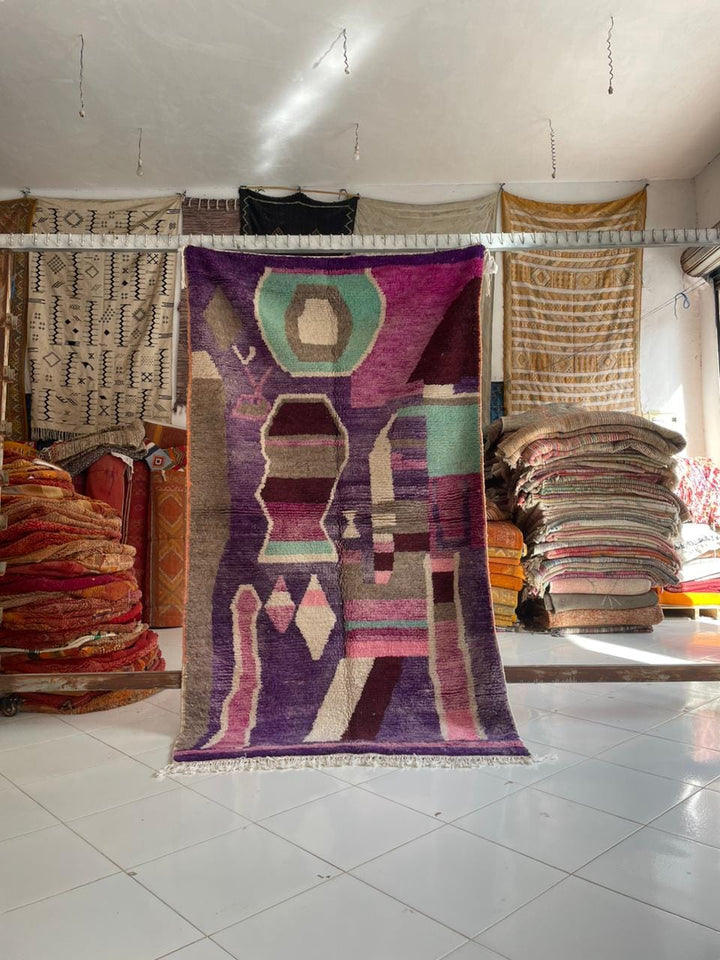 Lifestyle shot of a purple Moroccan rug with tribal patterns in a natural setting.