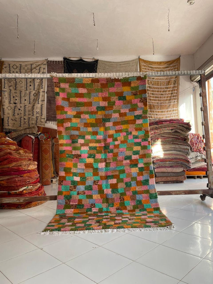 Lifestyle shot of a colorful Moroccan rug with orange, green, pink, and blue colors.