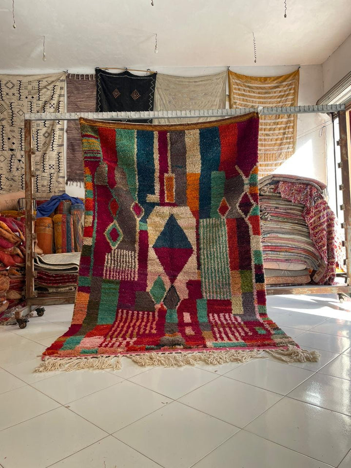 Lifestyle shot of a colorful Moroccan rug with fringe edges on a natural background.