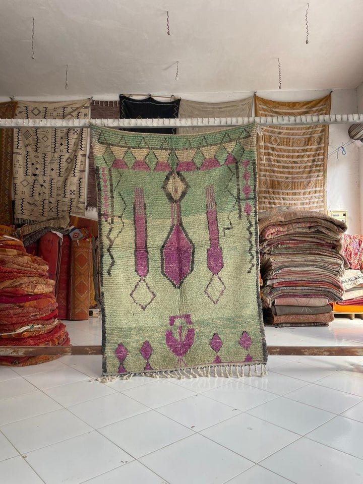 Lifestyle shot of a colorful Moroccan rug featuring tribal patterns and fringe edges.