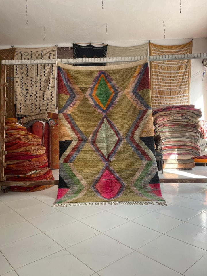 Lifestyle shot of a colorful Moroccan rug with geometric patterns in yellow, pink, and green.