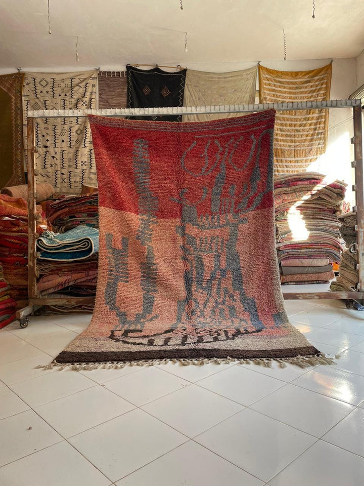 Lifestyle shot of a colorful Moroccan rug featuring tribal patterns in red, orange, and blue.