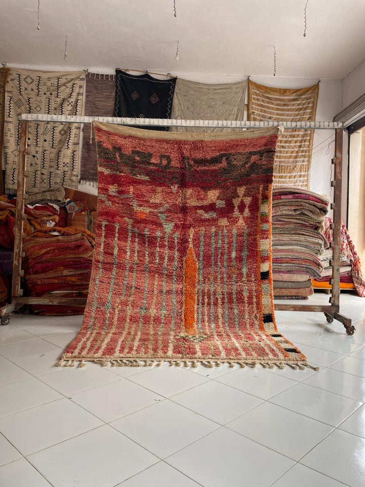 Lifestyle shot of a colorful Moroccan rug featuring geometric patterns and fringed edges.