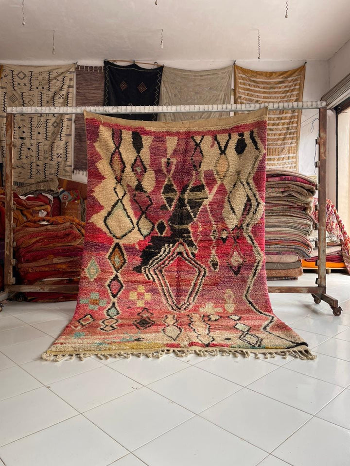 Lifestyle shot of a colorful Moroccan rug with intricate patterns and fringe edges.