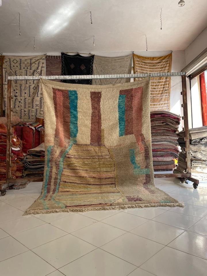 Lifestyle shot of a colorful Moroccan rug with beige, blue, and red tones in a natural setting.