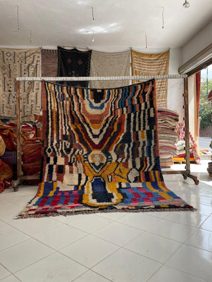 Lifestyle shot of a colorful Moroccan rug featuring geometric patterns in red, blue, yellow, and black.