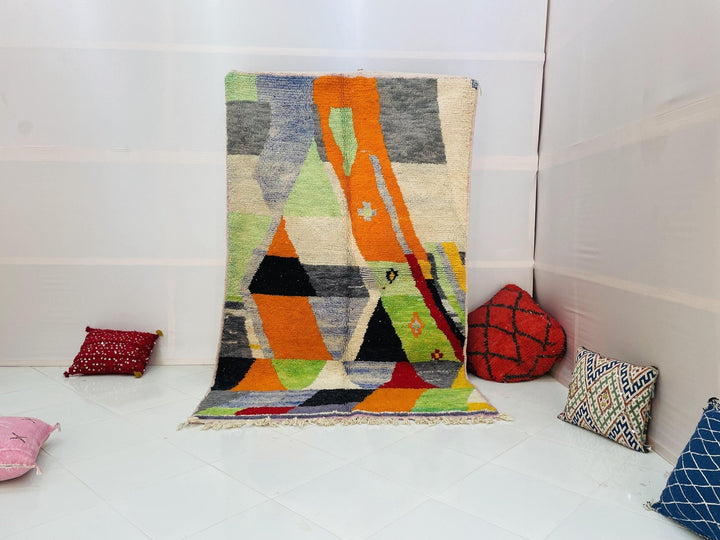 Lifestyle shot of an orange abstract Moroccan rug with geometric patterns on a white background.