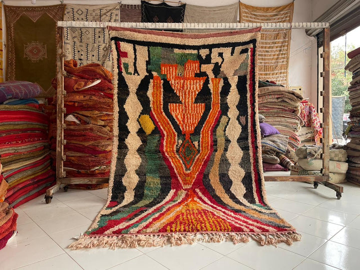 Lifestyle shot of a colorful Berber rug featuring geometric patterns in orange, green, and red.