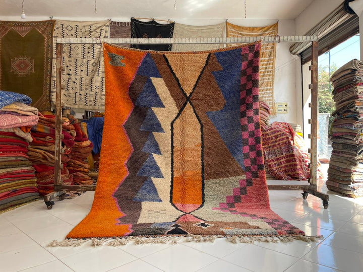 Lifestyle shot of a colorful Berber rug featuring geometric patterns and fringe edges.