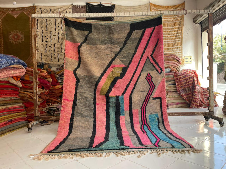 Lifestyle shot of a colorful pink Moroccan rug with geometric patterns in a natural setting.