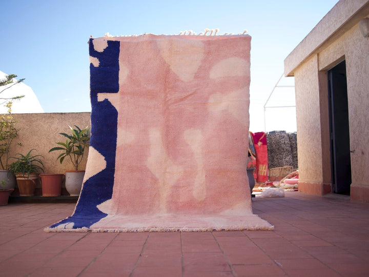 Lifestyle shot of a pink Beni Ourain rug featuring a geometric pattern in a natural setting.