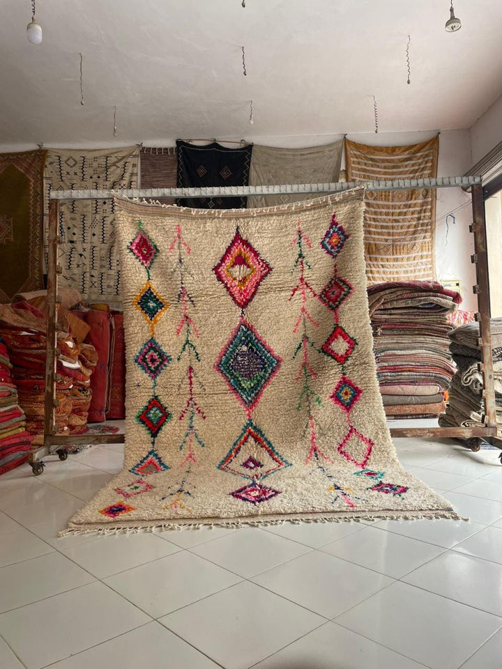 Lifestyle shot of a colorful vintage rug featuring geometric patterns and fringe edges.