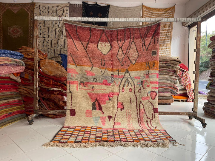 Lifestyle shot of a vintage Moroccan rug featuring geometric patterns in red, cream, and orange.