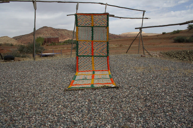 Lifestyle shot of a vintage kilim rug featuring geometric patterns in orange and green.