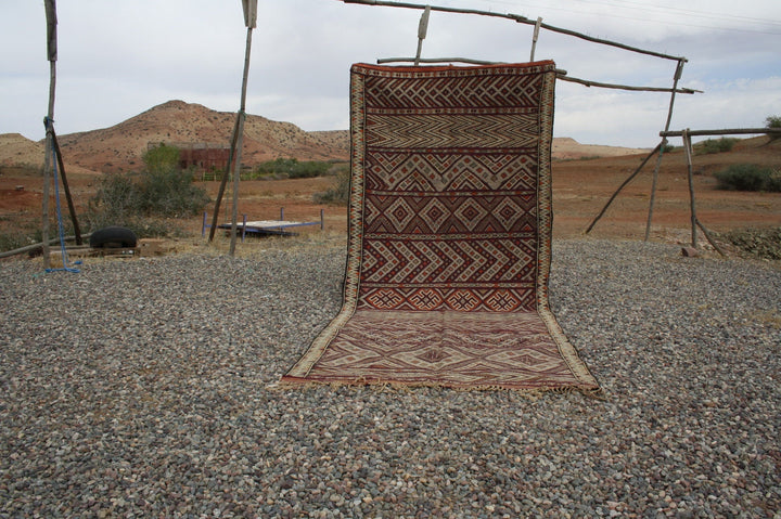 Lifestyle shot of a vintage kilim rug featuring geometric patterns in brown and beige.