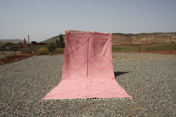 Lifestyle shot of a pink Moroccan rug with a textured surface in a natural setting.