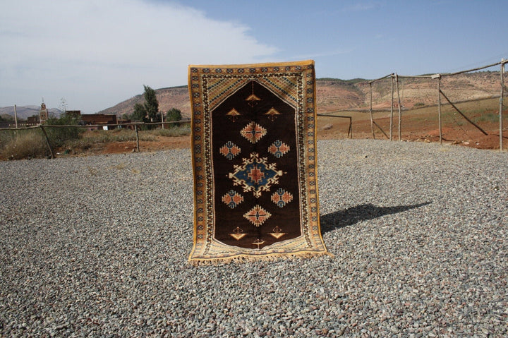 Lifestyle shot of a vintage kilim rug featuring geometric patterns in brown, orange, and blue.