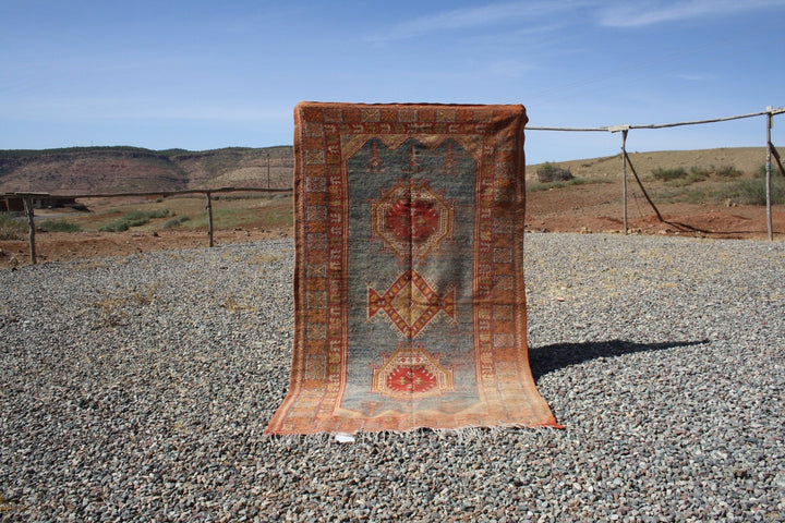 Lifestyle shot of a vintage kilim rug featuring geometric patterns in orange, blue, and red.