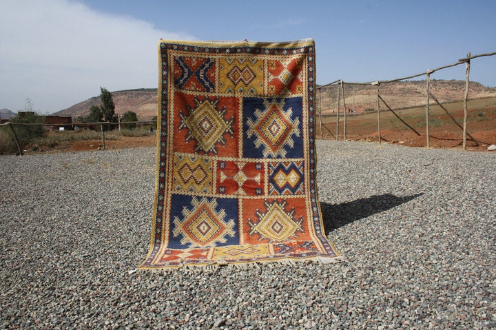Lifestyle shot of a vintage kilim rug showcasing geometric patterns in red, blue, and yellow.