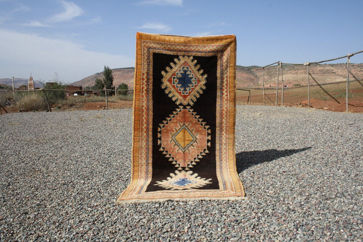 Lifestyle shot of a vintage kilim rug featuring geometric patterns in orange, blue, and black.