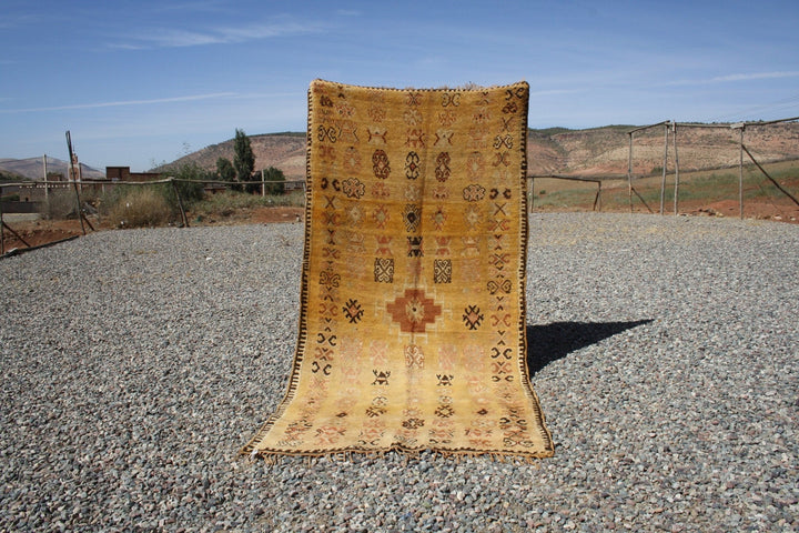 Lifestyle shot of a vintage kilim rug featuring geometric patterns in yellow, red, and black.