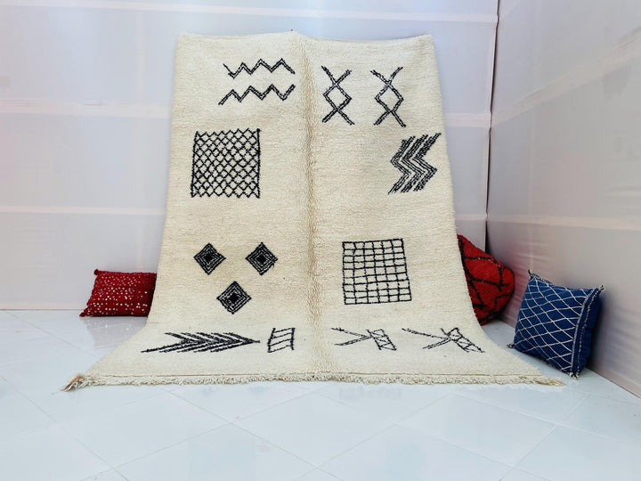 Lifestyle shot of a cream and black geometric Beni Ourain Moroccan rug on a white background.