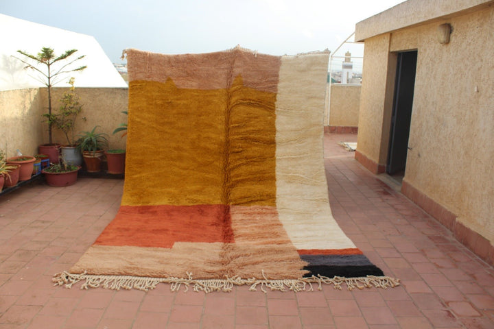 Front view of an orange and beige Beni Ourain rug with abstract design on a natural background.