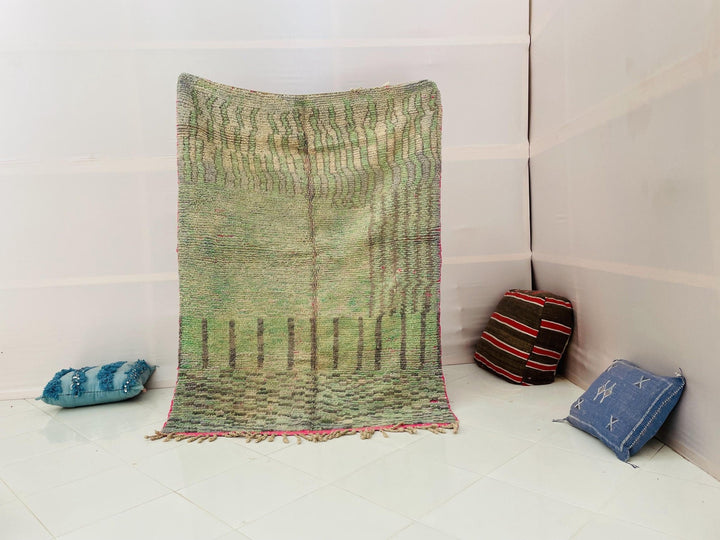 Lifestyle shot of the olive green vintage Moroccan rug with abstract design and fringed edges.