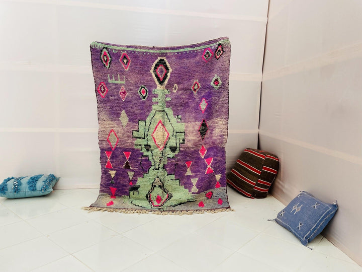 Lifestyle shot of a vintage Moroccan rug featuring abstract design in purple, green, and pink.