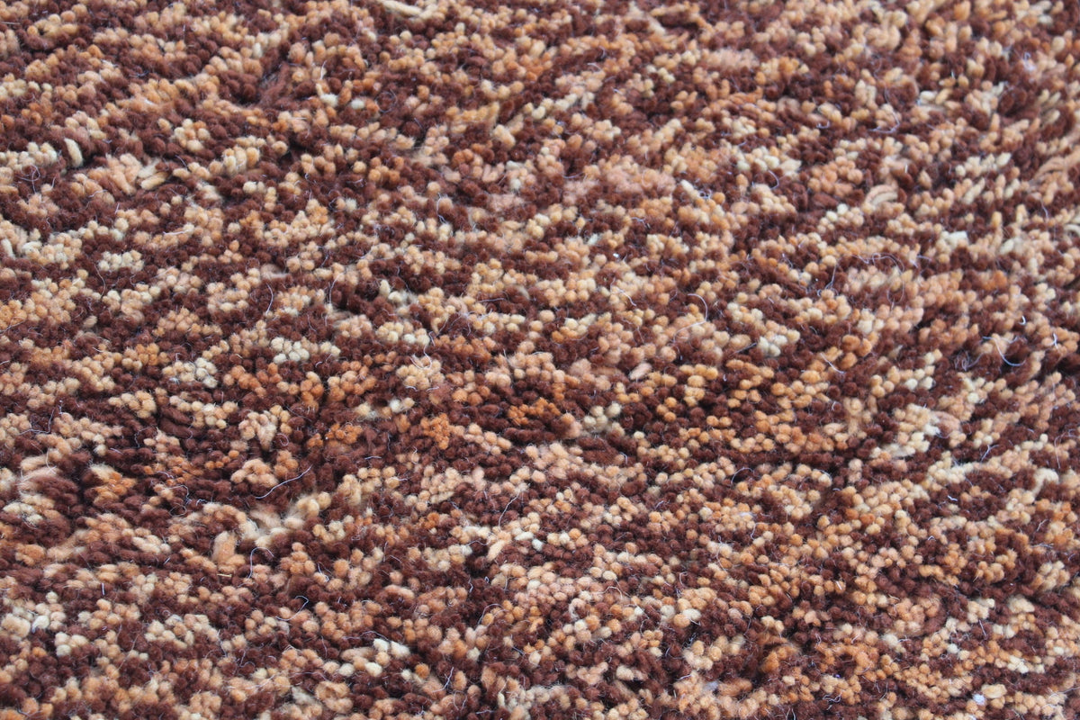 Detail shot of a Moroccan Beni Ourain rug showcasing a textured weave in brown and beige.
