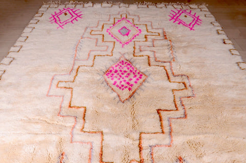 Close-up of a beige and pink Beni Ourain rug showcasing a soft texture and geometric patterns.