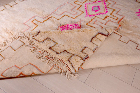 View of a beige and pink Beni Ourain rug with a diamond pattern, highlighting its handcrafted design.