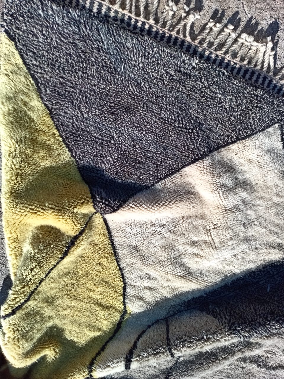 Side view of a Moroccan rug displaying its thick pile in gray and yellow shades.