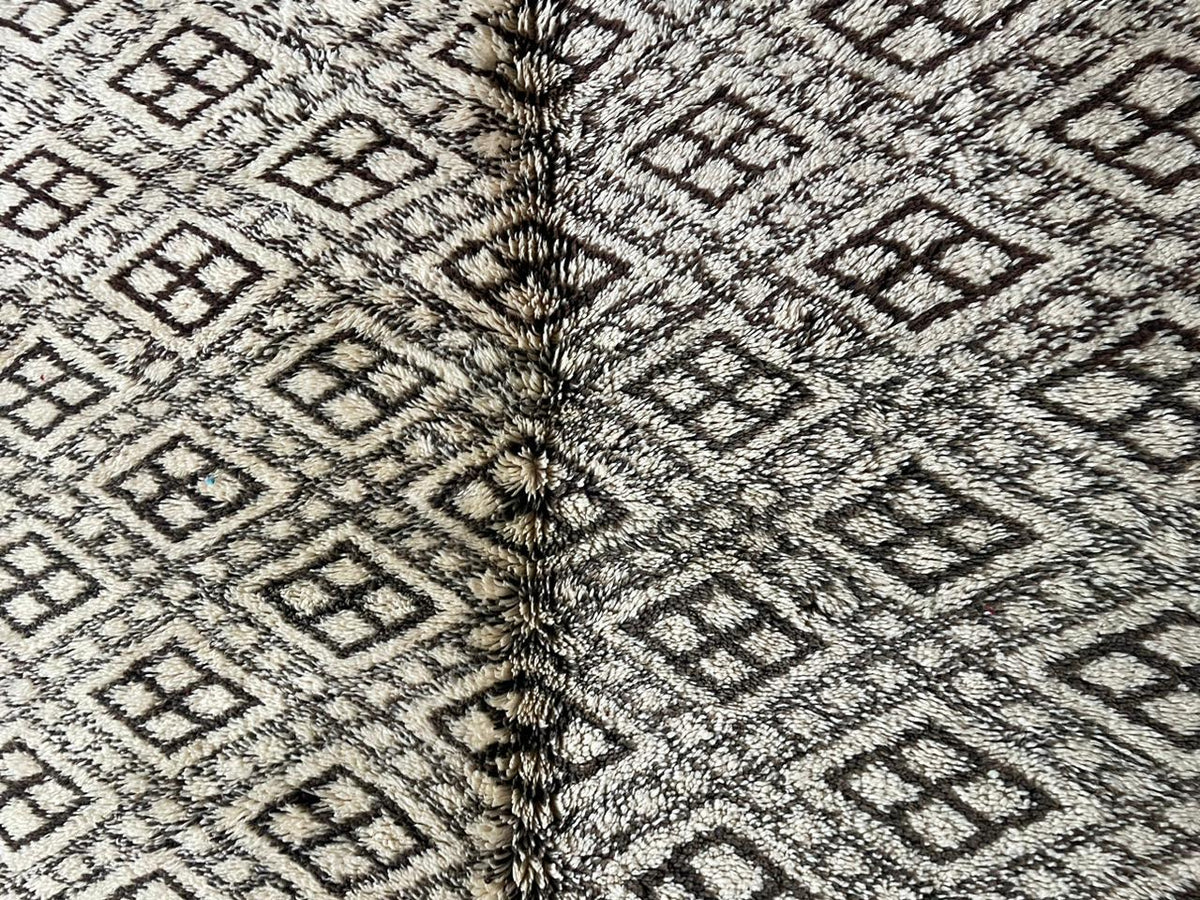 Close-up detail of a vintage Moroccan rug in gray and white featuring a diamond pattern and woven texture.