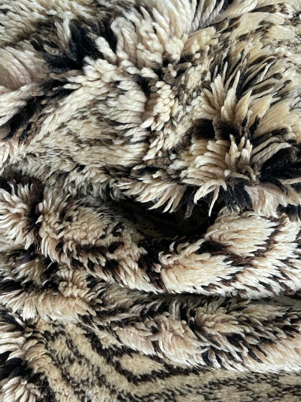 Close-up detail of a Moroccan rug in cream and black with a textured surface and abstract design.
